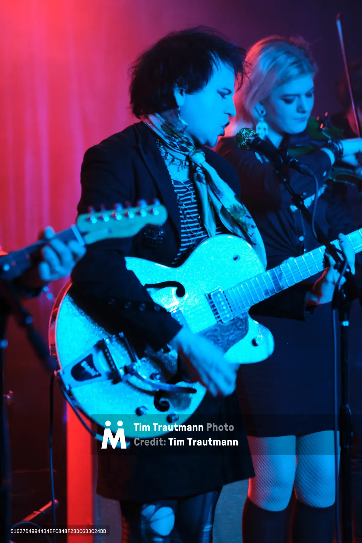 Charlotte McCaslin and Faith Grossnicklaus of Roselit Bone command the intimate stage at Dante's in Portland, bathed in ethereal blue and magenta lighting. McCaslin clutches a white hollow-body guitar while Grossnicklaus stands close beside her, both performers silhouetted against the venue's signature atmospheric glow. The dramatic color wash transforms the underground club into a dreamscape, capturing the raw intensity of their RX Fest 2019 performance.
