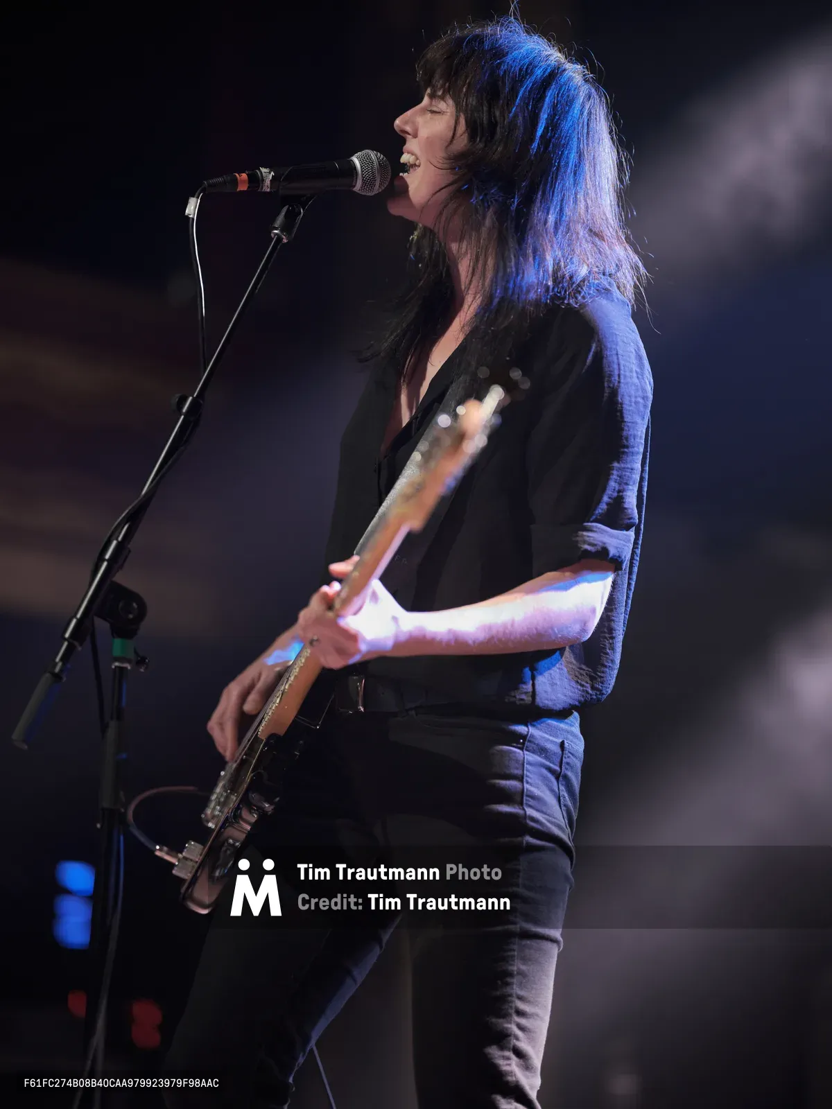 Emma Richardson of Band of Skulls delivers an impassioned performance during the band's 10 Year Anniversary Tour at Manhattan's iconic Webster Hall. Bathed in ethereal blue stage lighting, the bassist-vocalist leans into her microphone with raw intensity, her dark hair catching the atmospheric glow. The intimate venue setting creates a powerful connection between performer and audience, capturing the essence of indie rock's emotional authenticity.