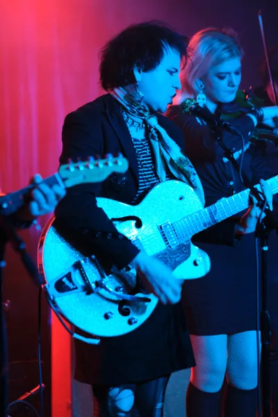 Charlotte McCaslin and Faith Grossnicklaus of Roselit Bone command the intimate stage at Dante's in Portland, bathed in ethereal blue and magenta lighting. McCaslin clutches a white hollow-body guitar while Grossnicklaus stands close beside her, both performers silhouetted against the venue's signature atmospheric glow. The dramatic color wash transforms the underground club into a dreamscape, capturing the raw intensity of their RX Fest 2019 performance.
