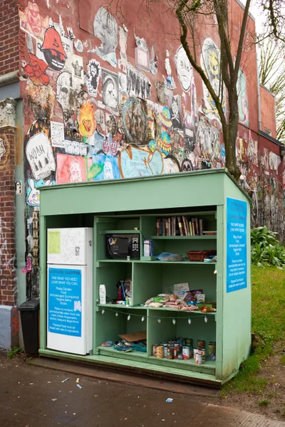 Community Fridge Against Graffitied Brick Wall