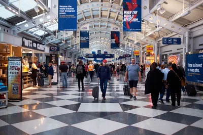Travelers Navigate Bustling O'Hare Terminal Concourse
