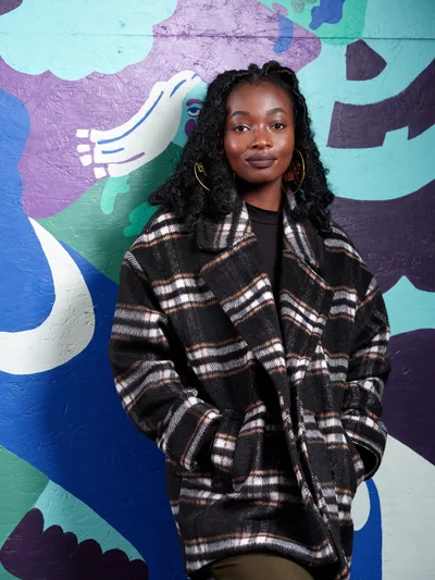 Artist Naomi Likayi Against Vibrant Mural Backdrop
